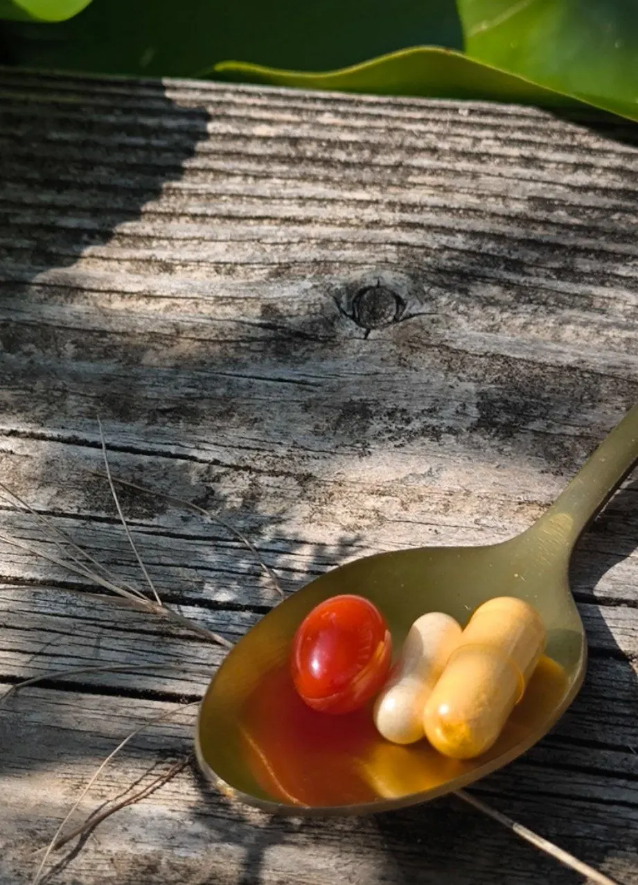 Bunte Kapseln auf einem Löffel auf verwittertem Holz